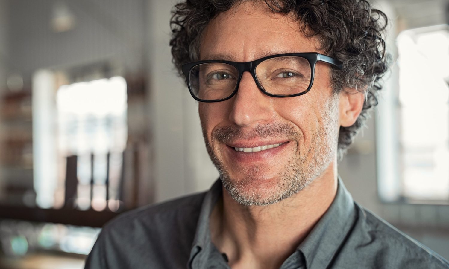 Portrait of mature businessman wearing glasses. Closeup face of smiling proud business man wearing eyeglasses and looking at camera. Satisfied senior man wearing spectacles indoor.